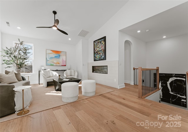 living room featuring ceiling fan, vaulted ceiling, and light wood-type flooring