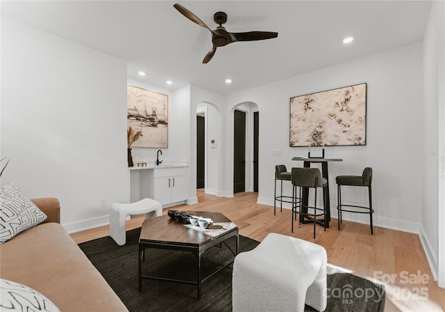 living room with ceiling fan, light hardwood / wood-style floors, and sink