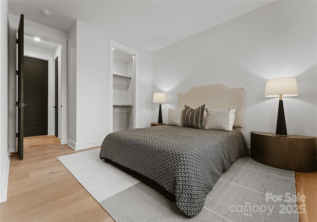 bedroom featuring wood-type flooring, a spacious closet, and a closet