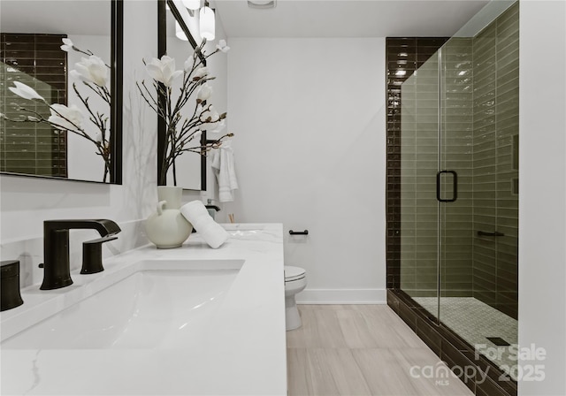 bathroom with a shower with door, vanity, and toilet