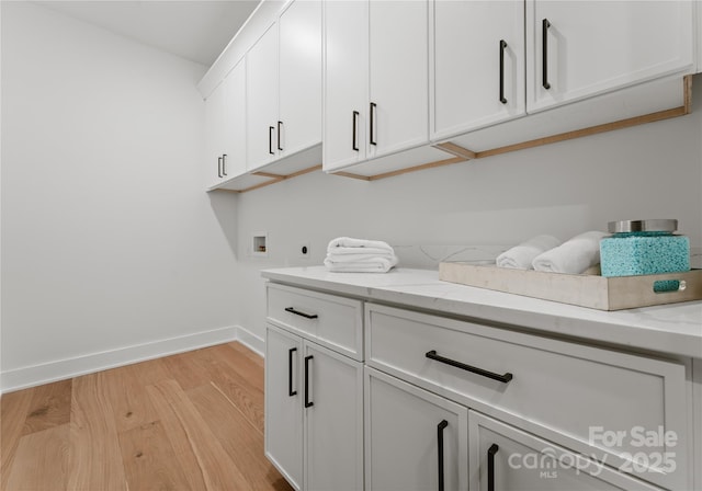 laundry area featuring washer hookup, electric dryer hookup, cabinets, and light wood-type flooring