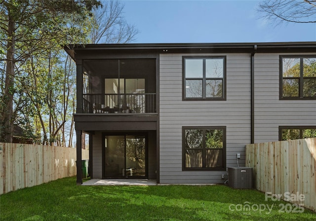 rear view of property featuring a balcony, central AC unit, and a lawn