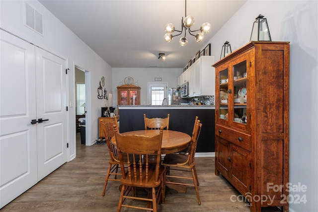 dining space with hardwood / wood-style floors and an inviting chandelier