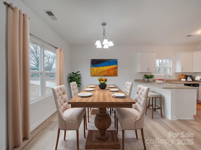 dining room with sink, light hardwood / wood-style flooring, and a chandelier