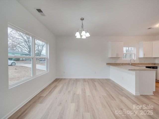 unfurnished dining area with sink, a chandelier, and light hardwood / wood-style floors