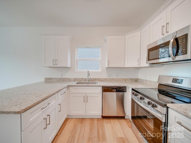 kitchen with white cabinets, sink, light stone counters, and stainless steel appliances