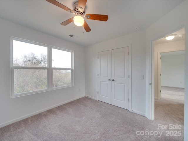 unfurnished bedroom with ceiling fan, light carpet, and a closet