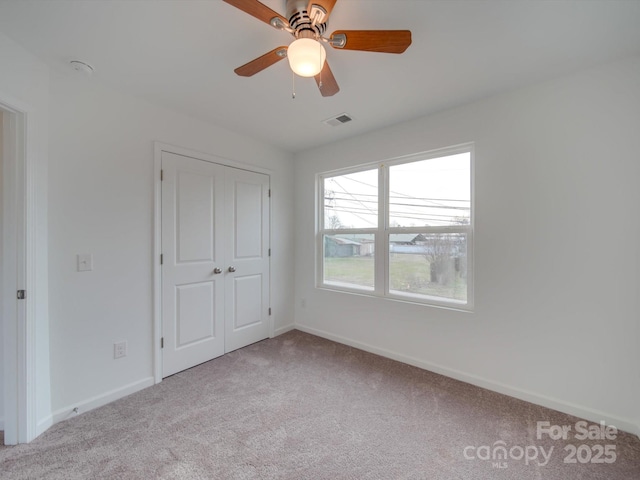 unfurnished bedroom featuring ceiling fan, a closet, and light colored carpet