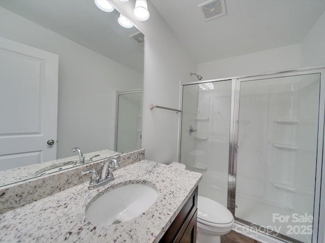 bathroom with a shower with shower door, toilet, and vanity