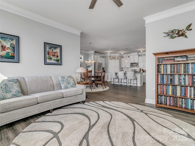 living room featuring ornamental molding, dark wood-type flooring, and ceiling fan with notable chandelier