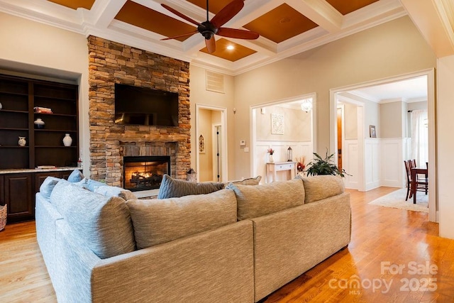 living room with beam ceiling, ceiling fan, coffered ceiling, a fireplace, and ornamental molding