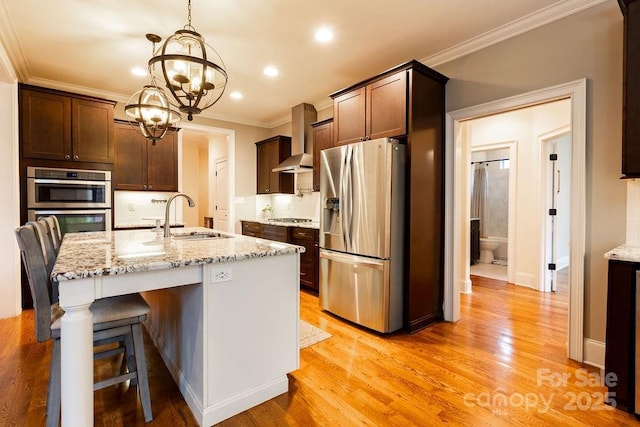 kitchen featuring pendant lighting, sink, wall chimney exhaust hood, a notable chandelier, and stainless steel appliances