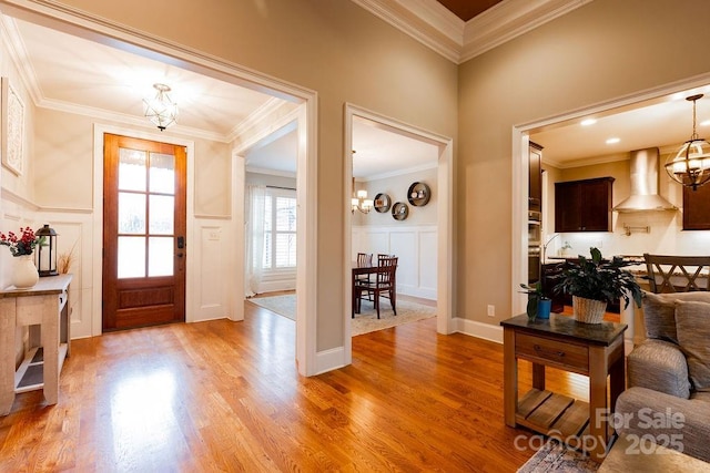 foyer entrance featuring light hardwood / wood-style floors, an inviting chandelier, and ornamental molding