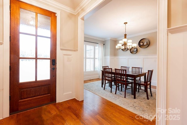 dining area featuring crown molding, wood-type flooring, and a notable chandelier