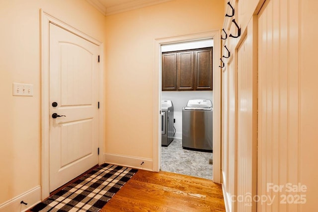 clothes washing area with washer and clothes dryer, cabinets, ornamental molding, and hardwood / wood-style floors