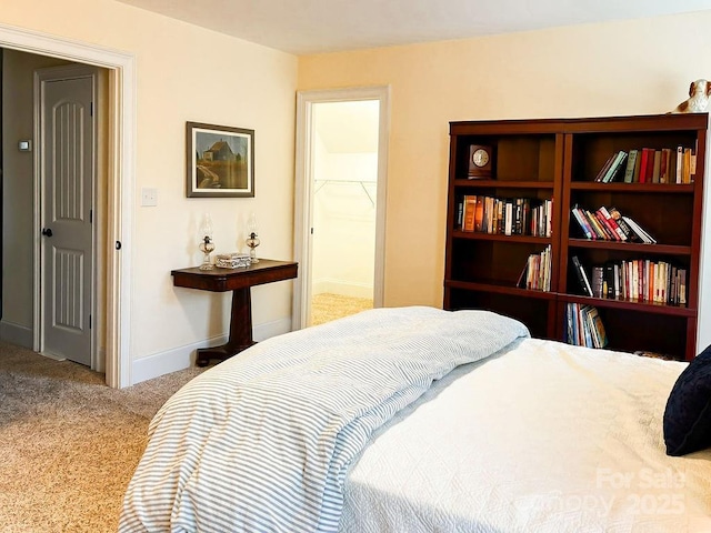 bedroom with a walk in closet, light colored carpet, and a closet