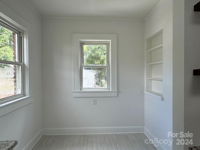 unfurnished room featuring built in shelves and a healthy amount of sunlight