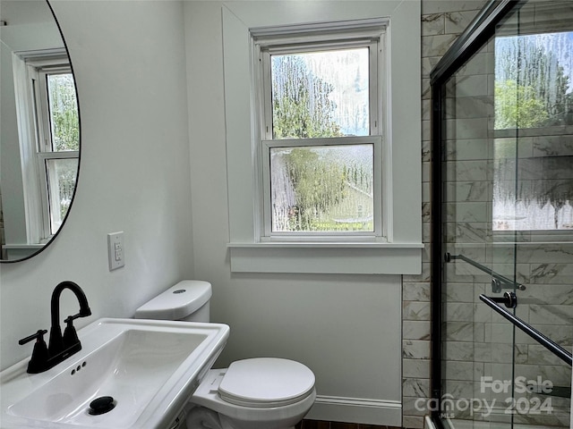 bathroom with toilet, a shower with shower door, and sink