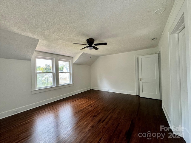 bonus room with a textured ceiling, dark hardwood / wood-style flooring, and vaulted ceiling