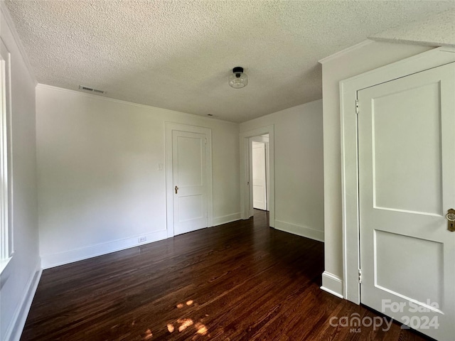 empty room with dark hardwood / wood-style floors, ornamental molding, and a textured ceiling