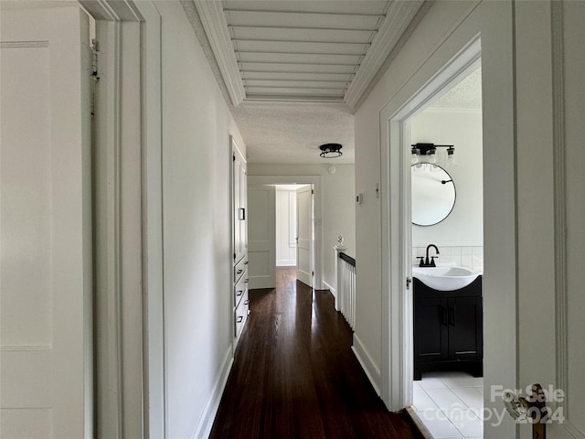 hallway with dark hardwood / wood-style flooring, ornamental molding, and sink