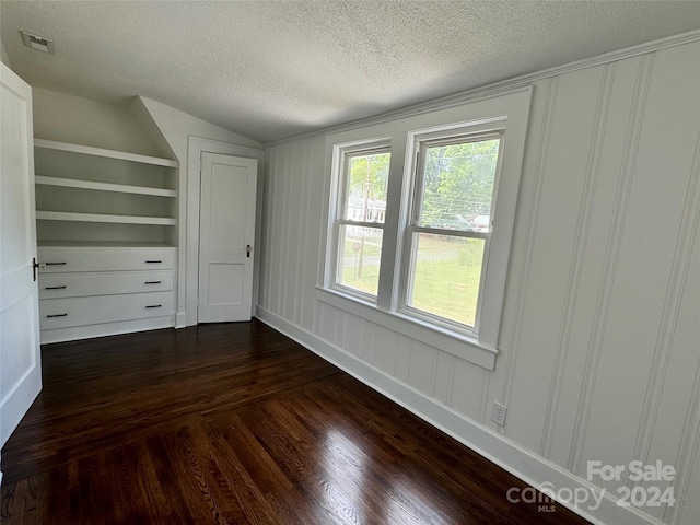 unfurnished bedroom featuring lofted ceiling, dark wood-type flooring, and a textured ceiling