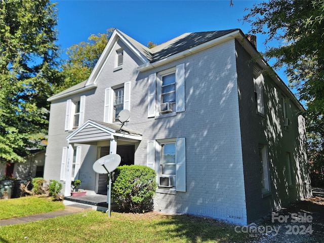 view of front of house with a front yard and cooling unit