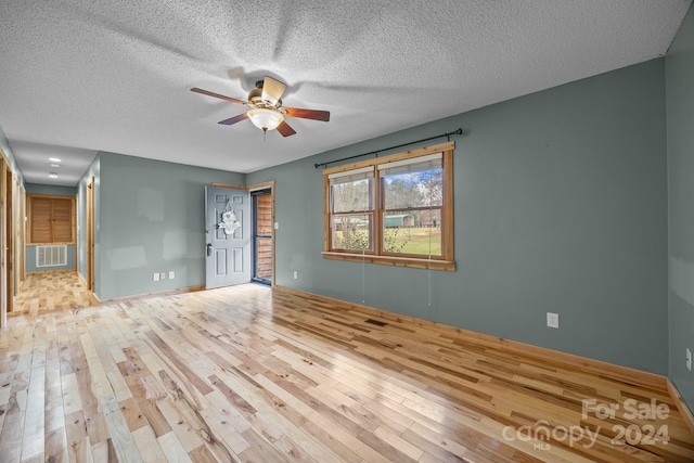 unfurnished room featuring a textured ceiling, light hardwood / wood-style flooring, and ceiling fan