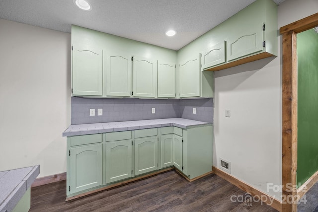 kitchen with tile counters, dark hardwood / wood-style flooring, a textured ceiling, and tasteful backsplash