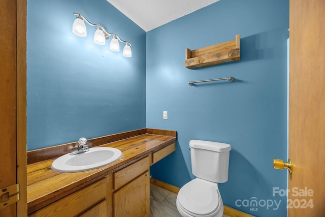 bathroom with tile patterned floors, vanity, a textured ceiling, and toilet