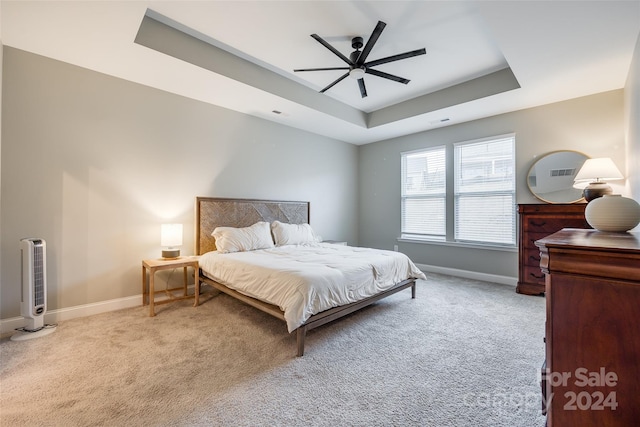 carpeted bedroom with heating unit, ceiling fan, and a tray ceiling