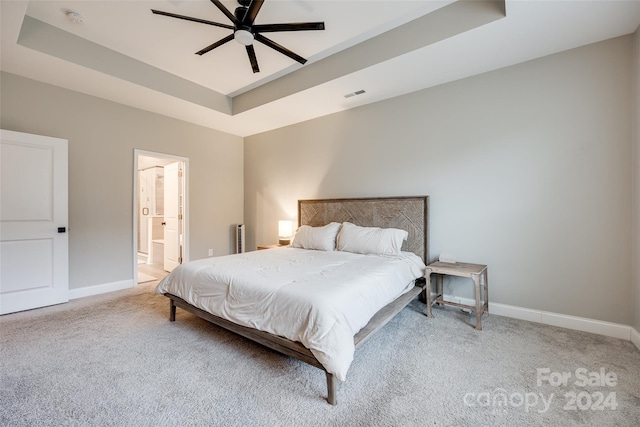 bedroom featuring a tray ceiling, ceiling fan, and ensuite bathroom