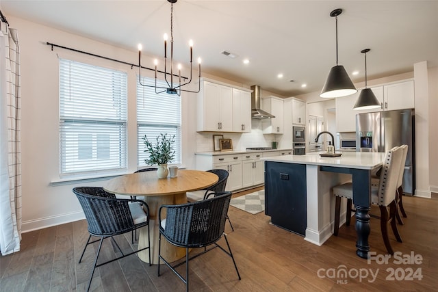 kitchen with wall chimney exhaust hood, dark hardwood / wood-style floors, white cabinetry, and a kitchen island with sink