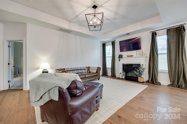 living room featuring light wood-type flooring, a wealth of natural light, and a notable chandelier