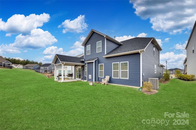 back of property with a yard, a patio, and central AC