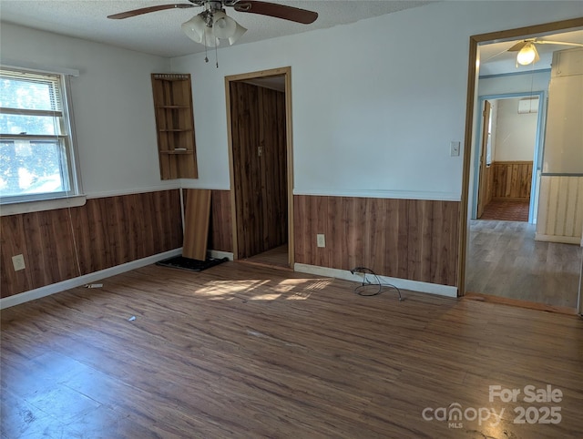 unfurnished room with dark hardwood / wood-style flooring, wooden walls, and a textured ceiling