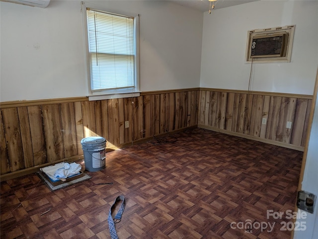 spare room featuring wooden walls, dark parquet floors, and a wall unit AC