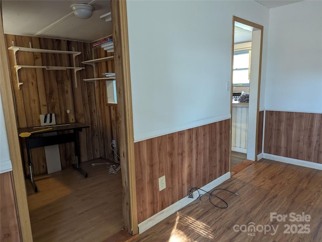 corridor featuring wood-type flooring and wood walls