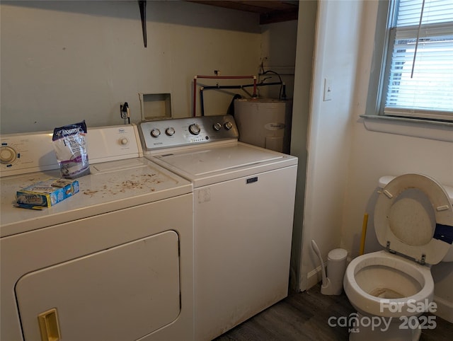 washroom featuring water heater, separate washer and dryer, and dark wood-type flooring