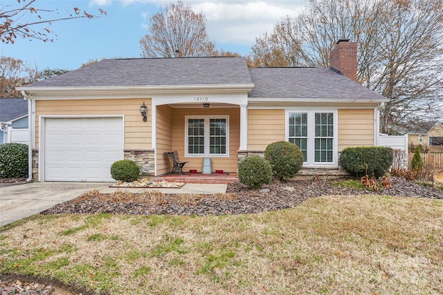 view of front of property with a porch, a garage, and a front lawn