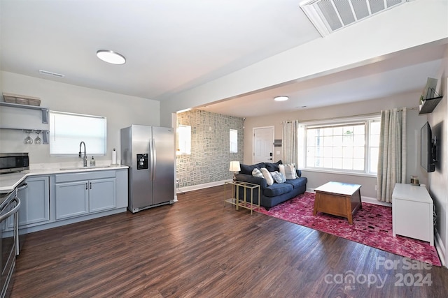 living room featuring sink, dark wood-type flooring, and brick wall