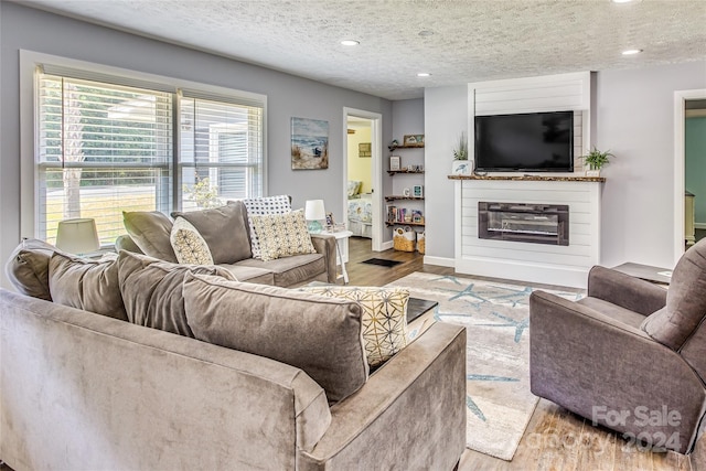 living room with a fireplace, a textured ceiling, and light hardwood / wood-style flooring