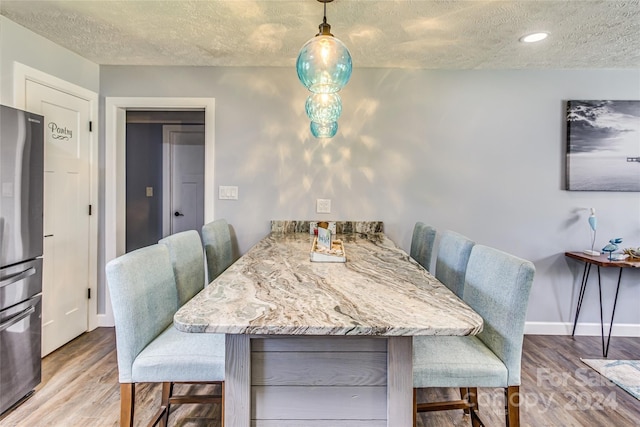 dining room with wood-type flooring, a textured ceiling, and breakfast area