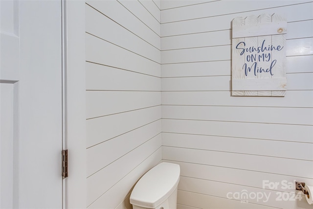 bathroom with wood walls and toilet