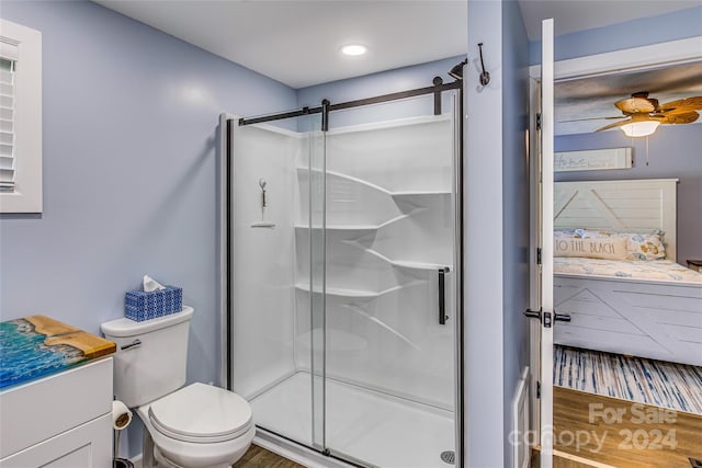 bathroom featuring vanity, hardwood / wood-style flooring, ceiling fan, toilet, and an enclosed shower