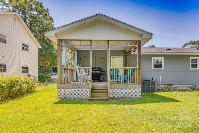 back of property with a porch, a yard, and central AC unit