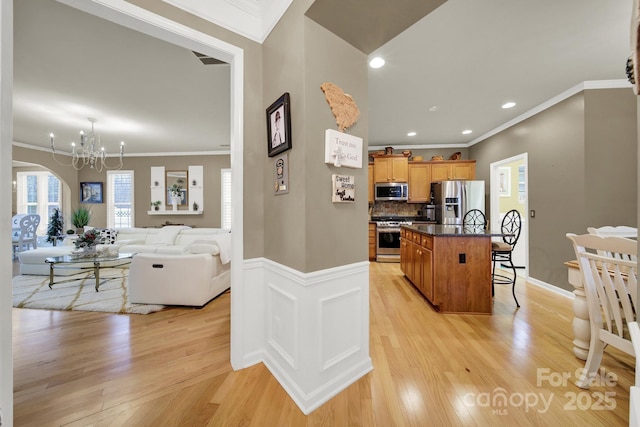 kitchen featuring a kitchen island with sink, light wood-type flooring, a breakfast bar area, and appliances with stainless steel finishes