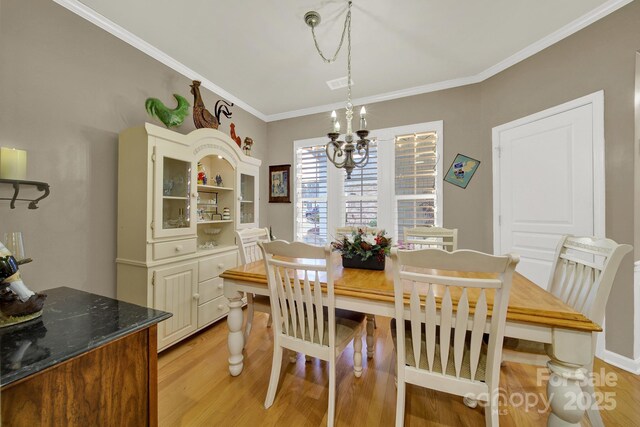 dining room featuring crown molding, a chandelier, and light hardwood / wood-style flooring