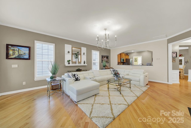 living room featuring a notable chandelier, ornamental molding, and light wood-type flooring