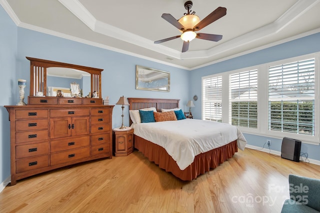 bedroom featuring crown molding, a raised ceiling, ceiling fan, and light wood-type flooring